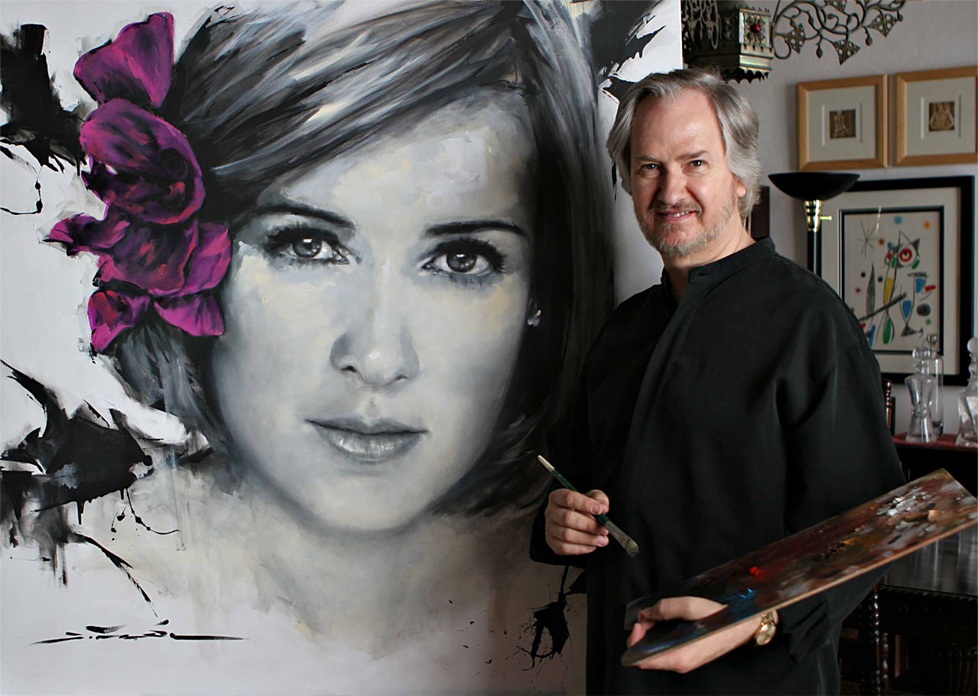 Jesús María del Rincón en su estudio, con paleta y pincel, junto a un retrato de gran formato.